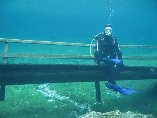 Submarinista sentado sobre el uente sumergido en el lago